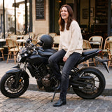 Motarde en jean moto femme Asfalt noir assise sur sa moto devant une terrasse