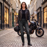 Motarde en jean moto femme Asfalt noir à côté de sa moto, le soir en ville